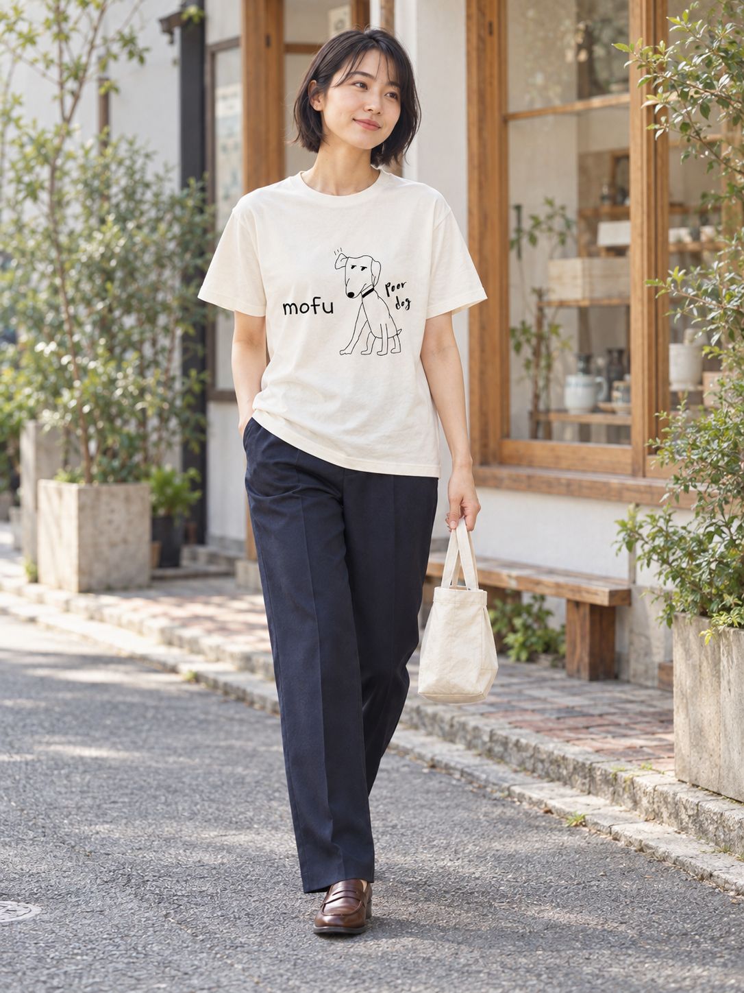 布バッグを提げて、小さな店の前の道をゆっくり歩く女性
